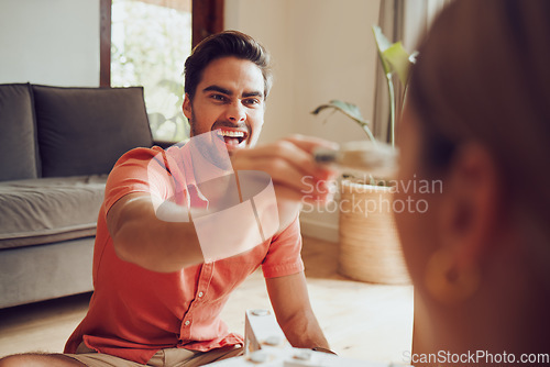 Image of Goofy, playful boyfriend painting face of girlfriend being silly. Fun couple doing home renovation, playing with paint and designing dream home while sitting together in the lounge at home.