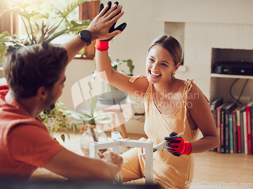 Image of Couple doing high five, well done or good job gesture while painting or remodelling furniture, wooden table for home improvement or interior decor. A man and woman with fun, creative DIY activity