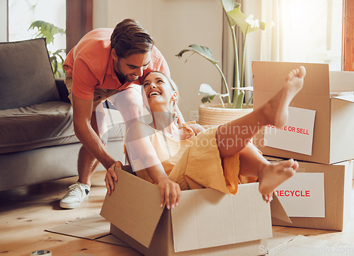 Image of Property, buying and fun couple moving into a new house together, being playful, bonding and unpacking. Happy young husband and wife playing with boxes, laughing and having fun being silly at home