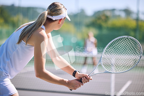Image of Active female tennis player back in motion holding racket, playing game match on outdoor sports court. Professional athlete training for sporty summer fun or fitness, health and wellness lifestyle.