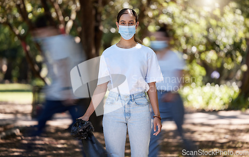 Image of Woman in covid face mask cleaning the park for clean, hygiene and safe green environment. Responsible activist, volunteer or community service worker with rubbish, trash and garbage in a plastic bag