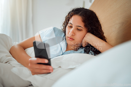 Image of Young woman checking phone and social media in bed, browsing internet after waking up to text message at home. Female relaxing, chatting online and streaming. Lady feeling lazy on the weekend