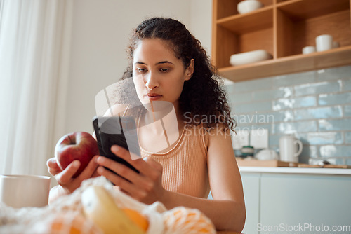 Image of Eating healthy, diet planning and personal online female dietitian. Serious nutritionist check phone, snack on fresh fruit and concentrating on social media. Communicate with patient about calories.