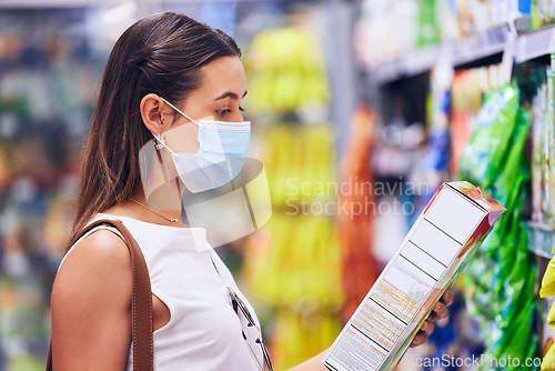 Image of Woman reading food box information or list at the grocery store, shop or supermarket. Trendy, young female shopping in covid pandemic with a mask for organic, fresh and healthy ingredients.
