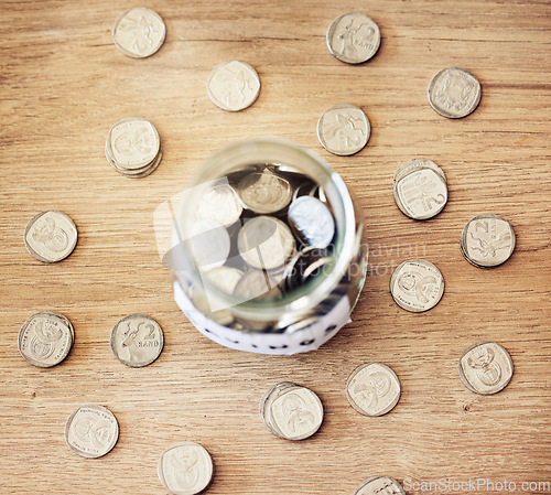 Image of . Savings, investment and a jar full of coins on a wooden table for future financial growth or insurance. Overhead view of an overflowing container with money for a donation or retirement fund.