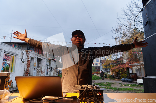 Image of A young man is entertaining a group of friends in the backyard of his house, becoming their DJ and playing music in a casual outdoor gathering