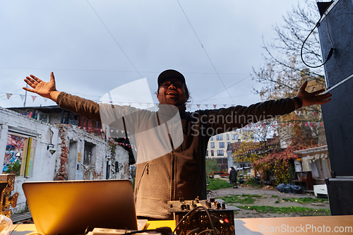 Image of A young man is entertaining a group of friends in the backyard of his house, becoming their DJ and playing music in a casual outdoor gathering