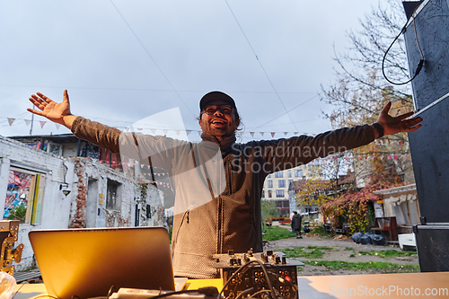 Image of A young man is entertaining a group of friends in the backyard of his house, becoming their DJ and playing music in a casual outdoor gathering