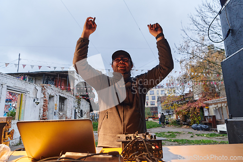 Image of A young man is entertaining a group of friends in the backyard of his house, becoming their DJ and playing music in a casual outdoor gathering