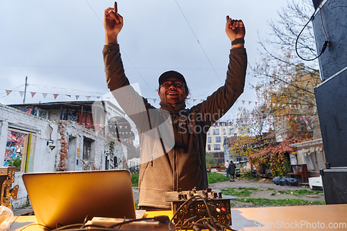 Image of A young man is entertaining a group of friends in the backyard of his house, becoming their DJ and playing music in a casual outdoor gathering