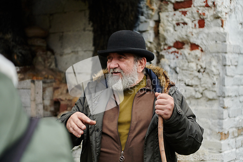 Image of An elderly man with a beard and a worn hat passionately imparts traditional values and cultural wisdom to others, embodying the essence of heritage preservation and storytelling.