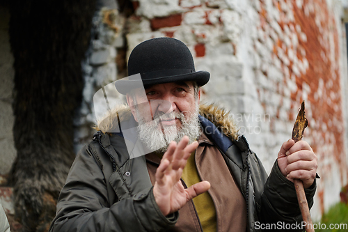 Image of An elderly man with a beard and a worn hat passionately imparts traditional values and cultural wisdom to others, embodying the essence of heritage preservation and storytelling.