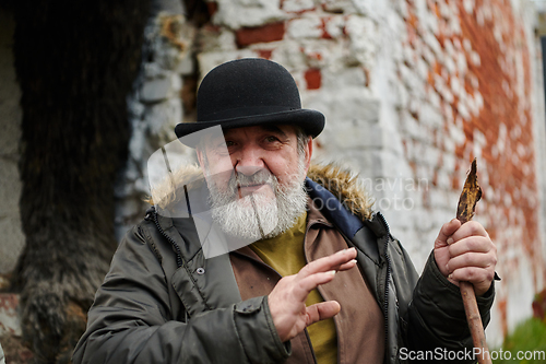 Image of An elderly man with a beard and a worn hat passionately imparts traditional values and cultural wisdom to others, embodying the essence of heritage preservation and storytelling.