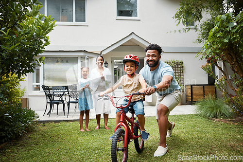 Image of Boy on bicycle learning with proud dad and happy family in their home garden outdoors. Smiling father teaching fun skill, helping and supporting his excited young son to ride, cycle and pedal a bike