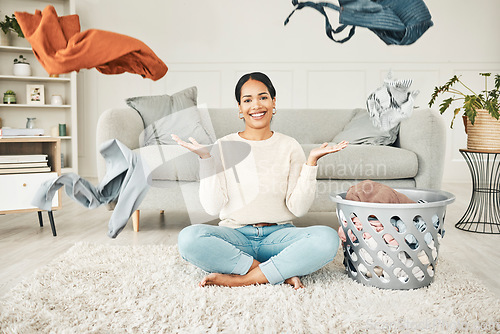 Image of Portrait of a cleaning, carefree female cleaner throwing clothing in the air. Happy, smiling and young woman doing laundry, washing clothes and sitting in a messy living room at home.