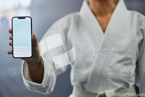 Image of . Blank phone screen and copyspace with a karate student holding the mobile display indoors. Sport person showing a copy space announcing a sale, marketing or social media advertising content.