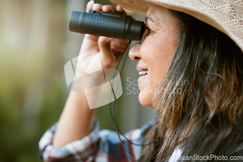 Image of . Nature, animal and bird watching of a smiling older woman looking and holding binoculars outside. Closeup of a mature female enjoying retirement relaxing on a day outdoors break feeling carefree.