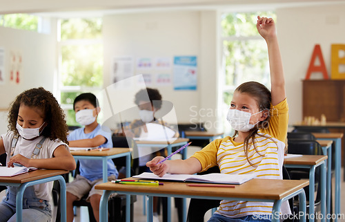 Image of Wearing face mask to protect from covid while learning in class, answering education question and studying with students in a classroom. Girl sitting at a desk and raising hand during a pandemic