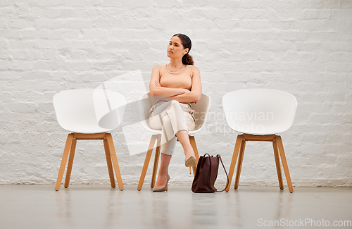 Image of Employment, hiring and recruitment with a young business woman sitting on a chair waiting for her interview with human resources. Female shortlist candidate looking impatient or nervous for a meeting