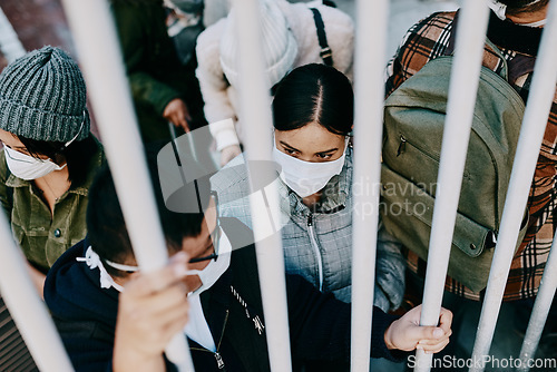 Image of Covid travel ban, lockdown or border control to prevent spread of pandemic virus, contagious disease or illness. Travelers in masks facing quarantine, abuse and discrimination behind locked gate
