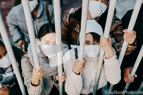 Image of Covid travel ban, lockdown or border control to prevent spread of pandemic virus, contagious disease or illness. Portrait of prisoners in masks facing racism and discrimination behind locked gate