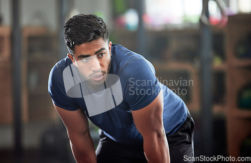 Image of Tired, breathing and fitness gym man taking a break from workout, training or exercising inside a wellness center. Young athletic, masculine guy resting after his strength or muscle exercise session