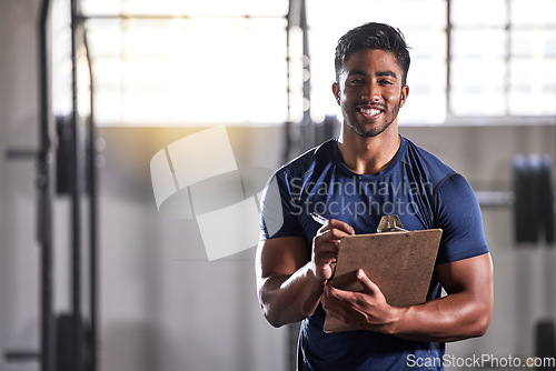 Image of Gym, workout and personal trainer with clipboard consulting at a training sports in gym. Portrait of muscular, active and smiling fitness coach writing on health, wellness and exercise with flare