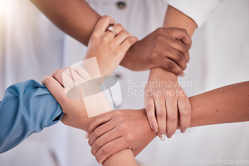 Image of Diverse colleagues hands holding wrists from above in support of unity, loyalty and teamwork in the workplace. Professional business synergy, trust and collaboration working towards strategy goal.