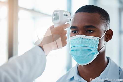 Image of Man with covid taking temperature with thermometer at hospital, checking for fever and wearing face mask to prevent risk of virus. Face of male examining health with doctor and doing checkup