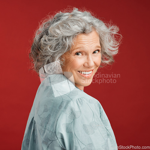 Image of .. Confident, happy and smiling senior woman feeling playful and cheerful while posing against red studio background. Portrait of a beautiful, older and retired lady looking back with grey hair.