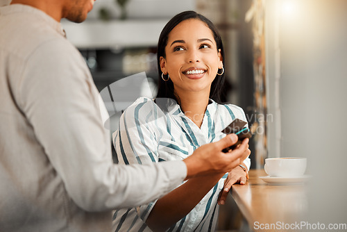 Image of Customer paying using contactless credit card, standing by cafe or restaurant bar counter. Smiling woman make cashless payment for coffee bill with wireless NFC tag reader technology POS machine.