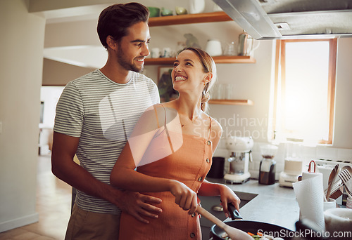 Image of Romantic, happy and young couple cooking dinner food and hug on a home date in a kitchen. Smiling dating partners relax feeling happiness, romance and love spending time at their house or apartment