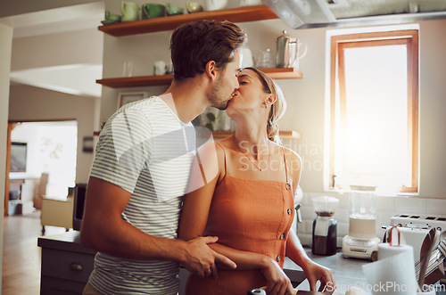 Image of Romantic couple kissing, cooking and showing affection in love while bonding together in a kitchen at home. Caring boyfriend and girlfriend in a loving relationship sharing an intimate special moment