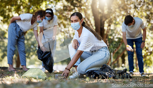 Image of Covid, volunteer and charity with a young woman doing community service and cleaning up the environment with people in the background. Portrait of an eco friendly environmentalist picking up trash