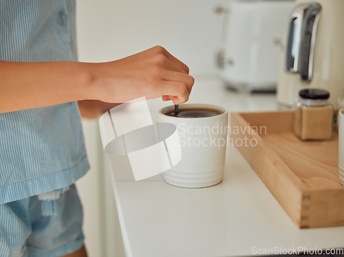 Image of Making fresh, hot morning coffee indoors on a kitchen counter to start the day. Hand closeup of preparing a warm beverage and drink inside with a female standing in pajamas at home