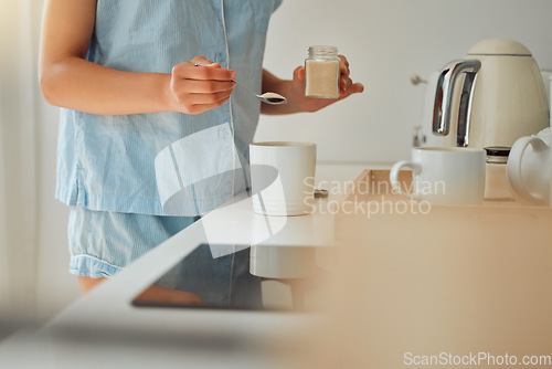 Image of Casual woman adding sugar while preparing a cup of coffee, tea or hot chocolate in the kitchen during the morning. Female hands holding teaspoon for a fresh beverage in a mug for breakfast at home