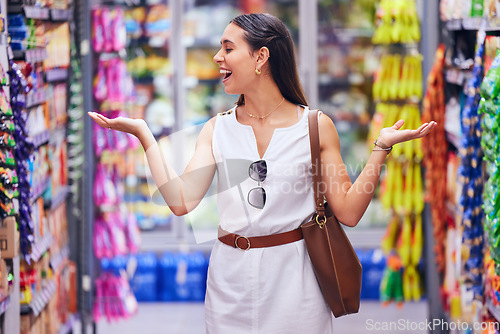 Image of Shopping, store and retail with a young woman customer at a supermarket or shop with products in the background. Money, buying and spending by a female consumer looking happy with options and variety