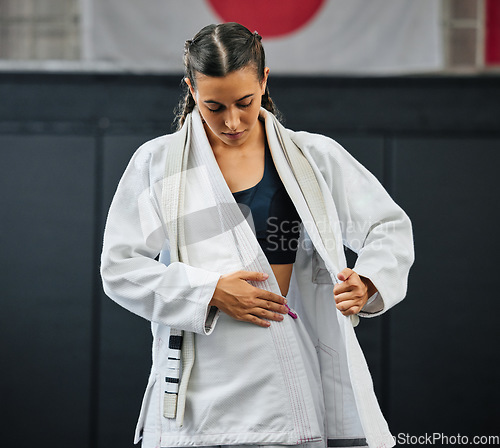 Image of . Female professional karate student dressing, wearing and preparing for practice, fight or training match in dojo. Woman mix martial art athlete tying uniform before competition or exercise workout.
