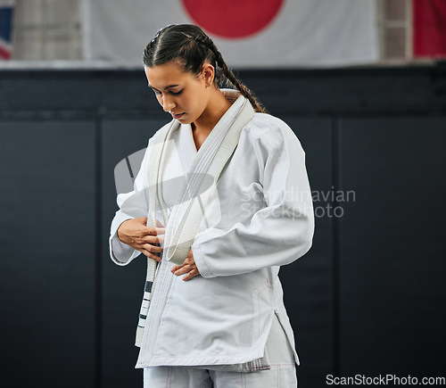 Image of Mma, karate and self defense with a young woman getting ready in her gi or uniform for training, exercise and practice. Workout, sport and fighting with a female athlete standing in a gym or studio