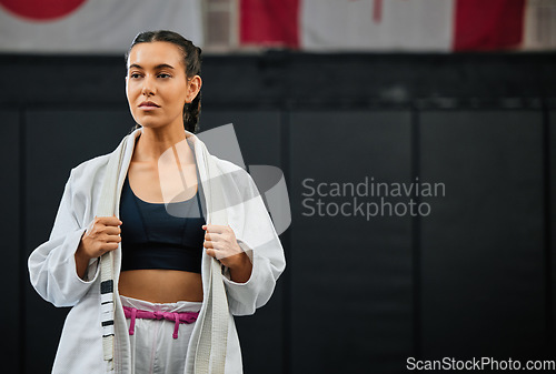 Image of . Mma, training and martial arts with a sporty young female fighter getting ready for a fit, match or competition in her gi or uniform. Training, exercise and sparring with a woman standing in a gym.