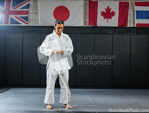 Image of Professional karate student dressing and prepare for practice in a dojo or club. Female mix martial art athlete tying belt in training for a fight, competition or exercise workout in a sport studio