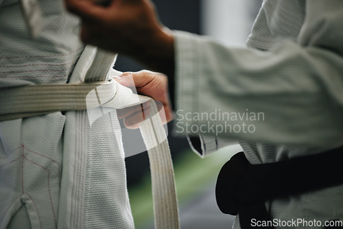Image of Karate learning, training and workout of a sport student and coach getting ready for a fight class. Defense expert hands tie a belt in a dojo, workout studio or wellness club about to work on fitness