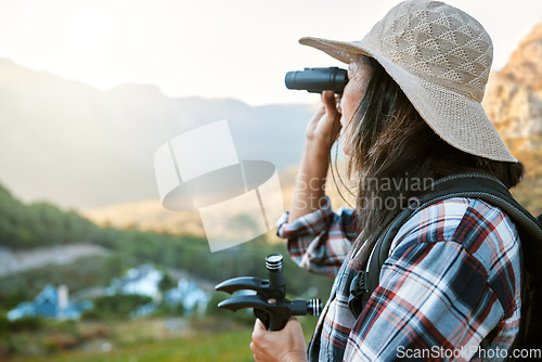 Image of Hiking, exploration and mountain adventure with binoculars, trekking pole and walking aid in a remote landscape with view. Mature woman, hiker and tourist watching birdlife or wildlife in eco nature