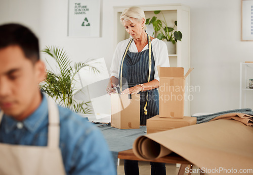 Image of . Fashion, design and style with a tailor, seamstress or creative designer packing boxes for shipment and delivery. Female stylist preparing a box to complete an order in her studio or workshop.