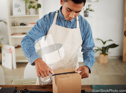 Image of Creative tailor closing order for shipping, seamstress packing product in a box for delivery and designer preparing a package at a shop. Male business owner, employee and courier working in a studio