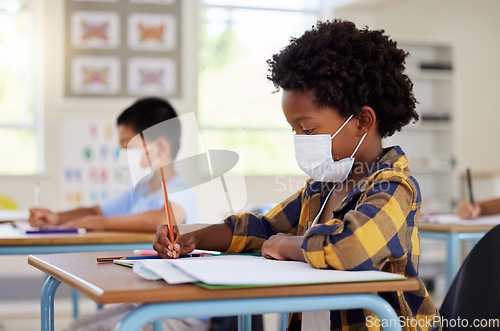 Image of School student in class during covid pandemic for learning, education and study with mask for safety, protection and protocol. Little kindergarten, preschool or elementary kid writing in book at desk