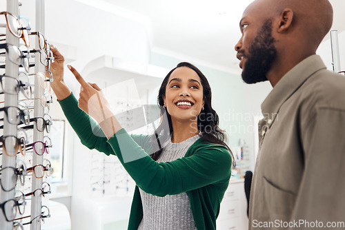Image of Smiling optometrist assisting man with glasses in a modern sale optometry store. Attractive lady in customer service helping young, African and healthy male choose and buy eyewear in a shop.