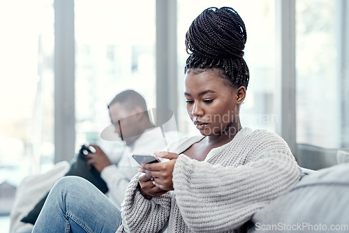 Image of Angry, serious and annoyed woman giving her boyfriend the silent treatment or cold shoulder after a fight, argument or disagreement as a couple. Female reading a text and ignoring her husband at home