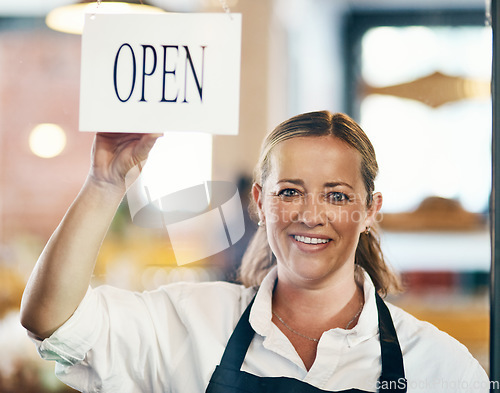 Image of Cafe owner opening her new startup, store or welcoming customers to a restaurant. Caucasian manager reopening her business after closing down. Waitress holding open sign at window or entrance.