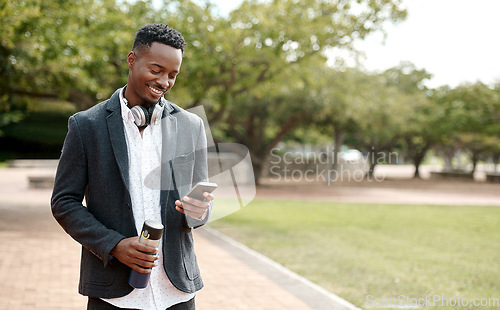 Image of Young, cool smiling businessman on a phone having a walk in the park outside in nature. Happy man texting, chatting or reading messages on a smartphone outdoors on a break from work, over copy space.